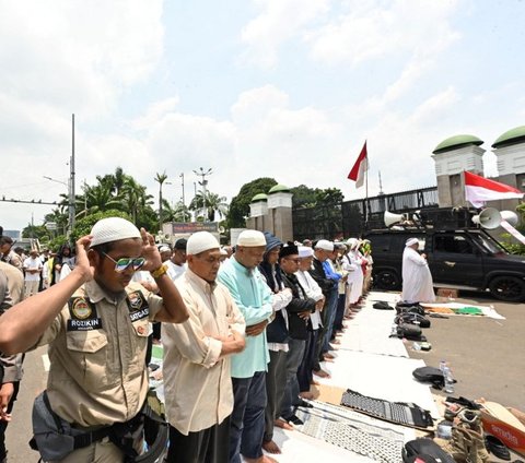 FOTO: Momen Pengunjuk Rasa Tuntut Hak Angket Gelar Jumatan di Depan Gedung DPR