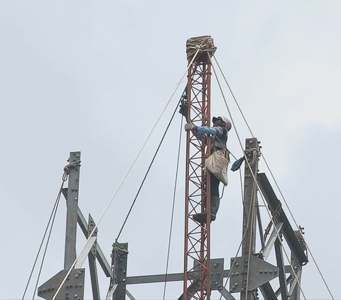 Pekerja memasang rangka baja  tiang saat membangun saluran transmisi di dekat Kanal Banjir Timur, Rawa Ujung Menteng, Jakarta, Rabu (13/3/2024). PT PLN (Persero) terus menggencarkan pembangunan infrastruktur kelistrikan secara masif. Merdeka.com/Imam Buhori