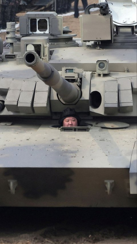 Dalam aksinya, Kim Jong-un terlihat berada di bawah moncong tank. Dia tampak memakai pelindung kepala khusus. Gayanya bak serdadu perang. Foto: KCNA via REUTERS