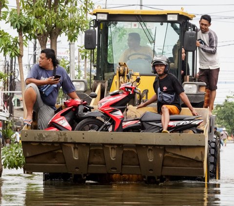 Sejumlah pengendara sepeda motor dievakuasi menggunakan buldoser saat banjir merendam salah satu kawasan di Kota Semarang, Jawa Tengah, Jumat (15/3/2024). Banjir yang terjadi sejak Kamis (14/3) dini hari masih merendam sejumlah titik di Ibu Kota Jawa Tengah tersebut. Devi Rahman/AFP