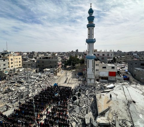 Serangan udara Israel telah menghancurkan tempat-tempat ibadah umat muslim di Gaza. Sudah banyak masjid rata dengan tanah. Namun dengan penuh ketabahan,  warga Palestina yang berlindung di Rafah, Jalur Gaza melaksanakan salat Jumat dekat reruntuhan masjid. Foto: REUTERS / Mohammed Salem<br>