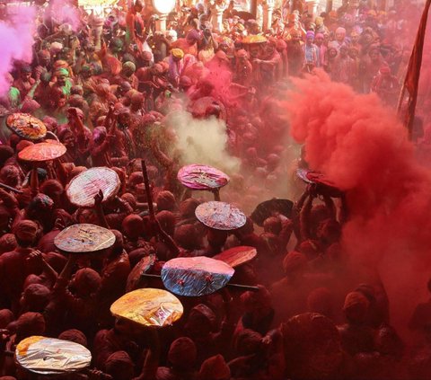 Sejumlah warga saling melempar bubuk warna-warni dalam Festival Lathmar Holi atau Festival Holi di sebuah kuil di Kota Barsana, Uttar Pradesh, India, pada 18 Maret 2024. Festival Holi yang identik dengan perang bubuk warna-warni kembali digelar di berbagai lokasi di India. REUTERS/Kishan Kumar Arora
