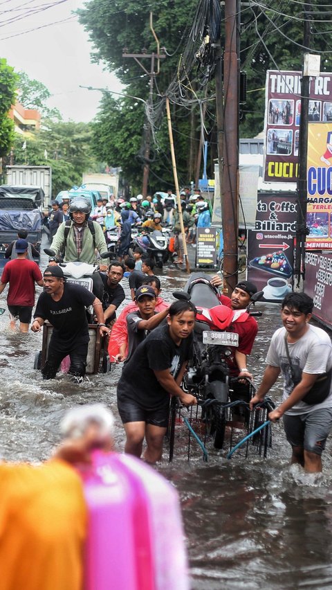 Warga menarik gerobak yang mengangkut sepeda motor saat banjir parah merendam jalur penghubung Jakarta-Tangerang di kawasan Joglo, Jakarta, Jumat (22/3/2024). Liputan6.com/Angga Yuniar