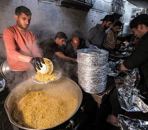 Hidangan itu dimasak oleh relawan dari organisasi kemanusiaan yang juga seorang pengungsi Barbara yang menyajikan makanan bagi orang-orang yang berbuka puasa di bulan suci Ramadan di Rafah. Foto: MOHAMMED ABED / AFP