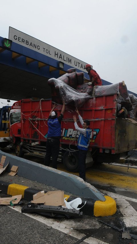 Petugas menaikkan muatan truk mebel yang berceceran setelah mengalami kecelakaan beruntun di depan Gerbang Tol Halim Utama, Jakarta, Rabu (27/3/2024). Foto: Merdeka.com/Imam Buhori