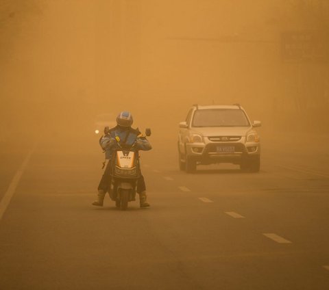 Seorang pengendara motor tampak berhati-hati ketika berkendara di tengah badai pasir yang menerjang Kota Jilin, Provinsi Jilin, China, pada 28 Maret 2024. Terpaan badai pasir parah yang melanda China ini disebabkan oleh cuaca dingin dan angin kencang. STR/AFP