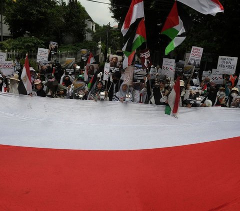 Peserta aksi bela Palestina membentangkan bendera merah putih di depan Kedutaan Besar Mesir, Jakarta, Senin (4/3/2024). Foto merdeka.com / Imam Buhori