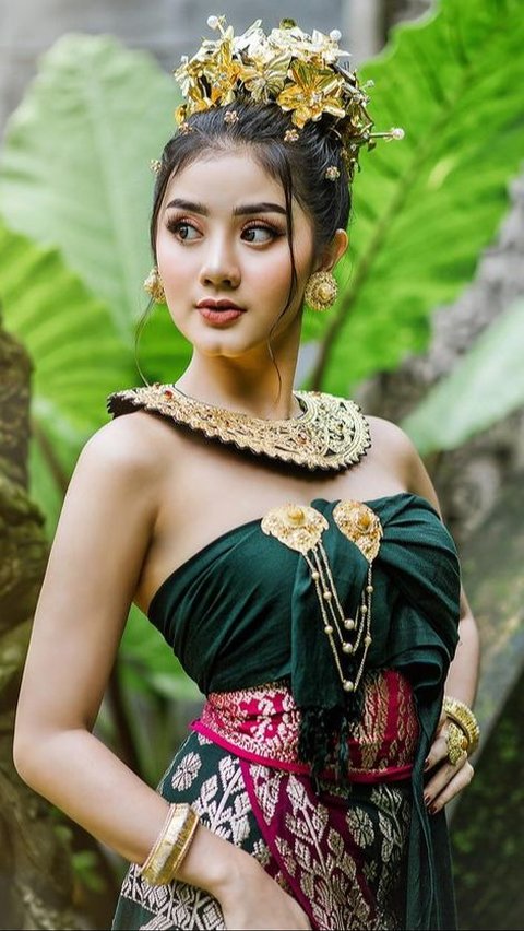 Ghea Youbi, seorang pedangdut, memancarkan kecantikan dengan busana adat Bali berwarna hijau tua.