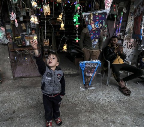 Seorang anak melihat lampu hias dan dekorasi yang dijual di sebuah toko di Deir al-Balah, Jalur Gaza bagian tengah, Palestina, pada 3 Maret 2024. Hanya dalam hitungan hari, umat Islam di seluruh penjuru dunia akan menyambut datangnya bulan suci Ramadan. AFP