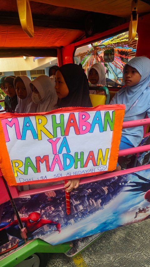 Murid SDI Al Hidayah membawa poster 'Marhaban ya Ramadan' saat mengikuti pawai tarhib Ramadan dengan menaiki odong-odong di kawasan Cinere, Depok, Jumat (8/3/2024). Merdeka.com/Arie Basuki