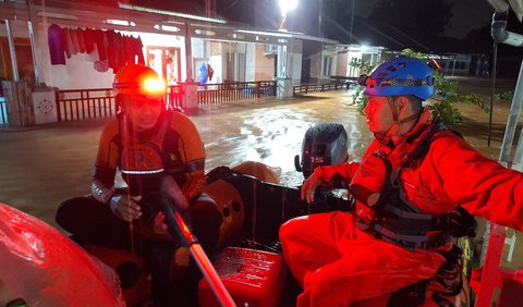 Tim SAR gabungan berpakaian lengkap berjibaku menggunakan perahu karet mengevakuasi warga.