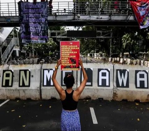 Seorang aktivis mengangkat poster saat berunjuk rasa memperingati Hari Perempuan Internasional di kawasan Patung Kuda, Jakarta, Jumat (8/4/2024). Liputan6.com/Angga Yuniar
