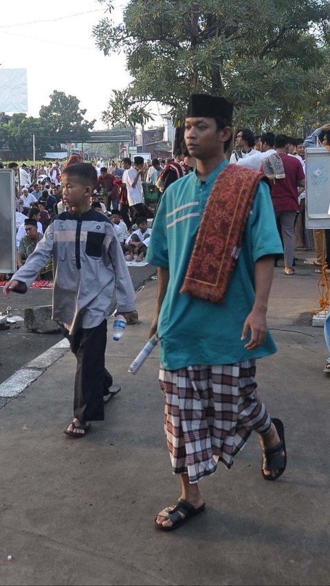 Jemaah yang baru datang terlihat membawa koran yang akan digunakan sebagai alas untuk salat Idulfitri. Foto: merdeka.com / Imam Buhori