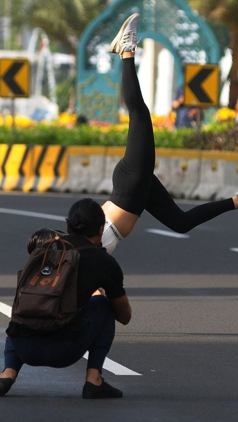 Warga mengabadikan momen seorang wanita saat melakukan foto atraktif di tengah jalan protokol Jakarta. Foto: merdeka.com / Imam Buhori