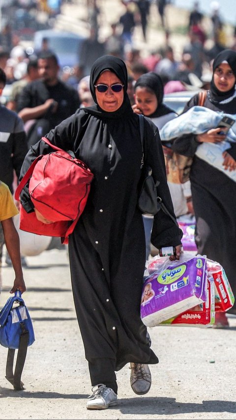 Warga Palestina membawa barang-barangnya saat berjalan kaki untuk kembali ke Kota Gaza melewati Nuseirat di bagian tengah Jalur Gaza, pada Minggu (14/4/2024). AFP