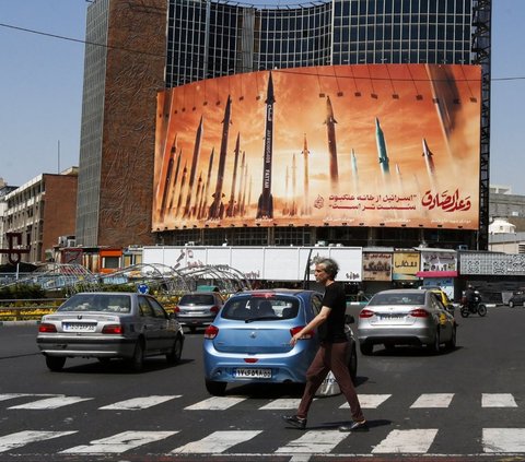 Seorang pria menyeberangi jalan di tengah lalu lintas yang ramai di Ibu Kota Teheran, Iran, Jumat (19/4/2024). Israel dilaporkan melancarkan serangan rudal terhadap fasilitas nuklir Iran di Isfahan sebagai balasan atas serangan pada akhir pekan lalu. AFP