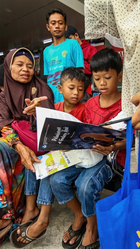 Tampak wajah ceria dari anak-anak yang hendak mudik saat membaca buku yang diberikan gratis oleh Badan Bahasa Kemendikbudristek di Teriminal Kalideres. Foto: Liputan6.com / Angga Yuniar