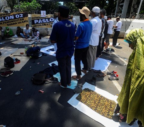 Aksi ini diikuti massa dari Koalisi Nasional Penyelamat Demokrasi (KNPD).<br><br>Mereka mengambil wudhu di air kolam Patung Kuda dan melaksanakan salat dzuhur berjemaah di area Jalan Medan Merdeka Barat. Foto: merdeka.com / Arie Basuki<br>