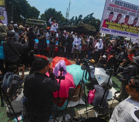 Massa Kubu Paslon 01 Anies Baswedan-Muhaimin Iskandar dan 03 Ganjar Pranowo-Mahfud Md  melakukan shalat dzuhur berjamaah saat menggelar aksi demonstrasi di Patung Kuda, Gambir, Jakarta Pusat, Senin, (22/04/ 2024) .Aksi demonstrasi tersebut saat pembacaan putusan Mahkamah Konstitusi (MK) dalam sidang Perselisihan Hasil Pemilihan Umum (PHPU) atau sengketa Pilpres 2024.