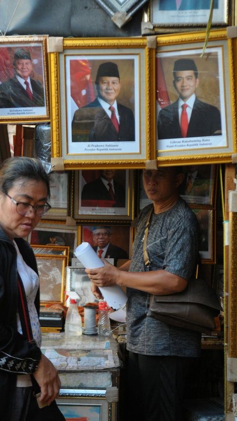 Pedagang bingkai foto saat melayani pembeli yang memesan gambar tersebut di Pasar Baru Jakarta, Senin (22/4/2024). Foto: merdeka.com / Imam Buhori