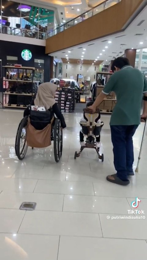 Beginilah gambaran ketika kedua orang tua disabilitas mengajak putrinya jalan-jalan di mall. Sang istri memakai kursi roda, sementara sang suami memakai tongkat sambil mendorong sepeda roda tiga putrinya.