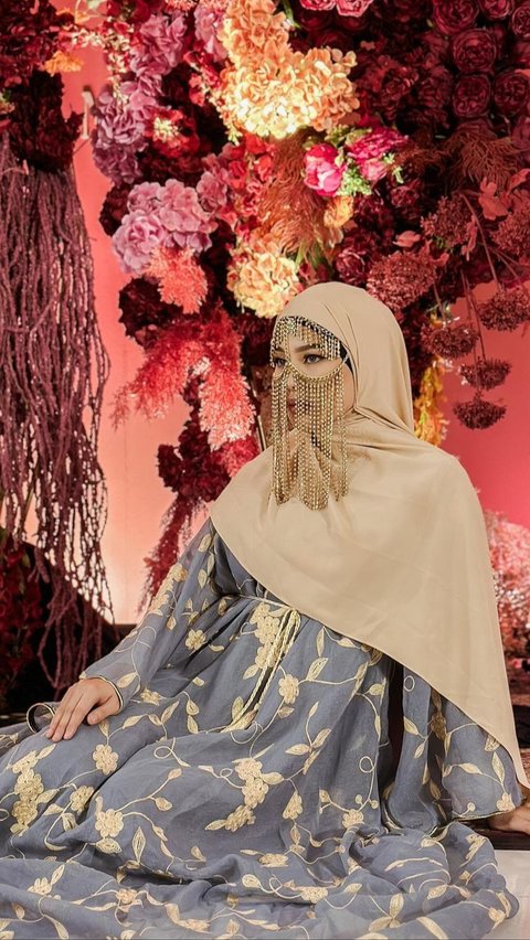 Dara Arafah dengan abaya warna biru muda yang dipadukan hijab krem dan chain face mask seperti Inara Rusli.
