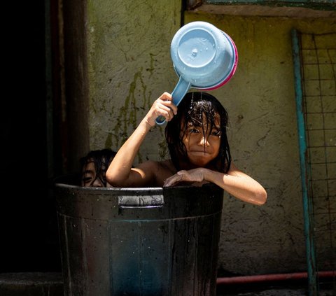 Dua orang anak berendam di sebuah ember ketika panas menyengat menyerang Kota Manila, Filipina, Kamis (25/4/2024). Panas ekstrem dengan suhu hampir menyentuh 50 derajat Celcius melanda sejumlah negara di Asia Tenggara, seperti Thailand dan Filipina. REUTERS/Eloisa Lopez