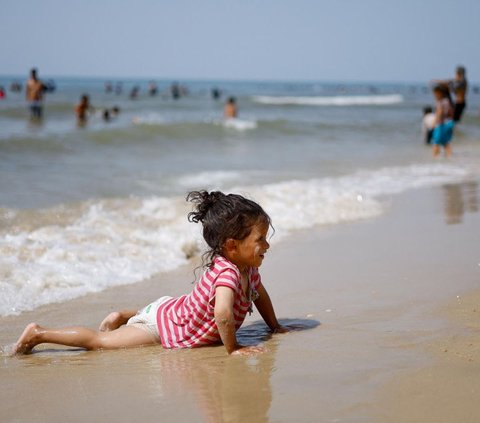 Sebagian dari anak-anak terlihat bermain air di tepi pantai.<br><br>Mereka datang ke pantai untuk mengalihkan pikirannya sejenak dari kehancuran akibat perang dengan Israel. Foto: REUTERS / Mohammed Salem<br>