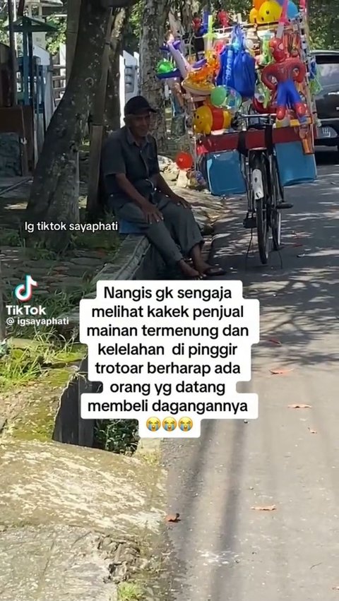 Inilah momen saat kakek penjual mainan duduk termenung di trotoar sambil berharap ada yang membeli dagangannya.