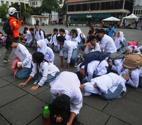 Sejumlah siswa merunduk ketika sirine gempa meraung-raung dalam simulasi yang digelar pada Hari Kesiapsiagaan Bencana 2024 di kawasan Kota Tua, Jakarta, Jumat (26/4/2024). Relawan yang tergabung dalam Tim Penanggulangan Bencana Indonesia menggelar peringatan Hari Kesiapsiagaan Bencana (HKB) yang jatuh pada 26 April. Foto: Merdeka.com/Imam Buhori