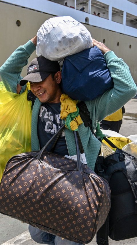 Penumpang membawa barang-barangnya saat tiba di Pelabuhan Tanjung Perak, Surabaya, Jawa Timur, Rabu (3/4/2024). Juni Kriswanto/AFP