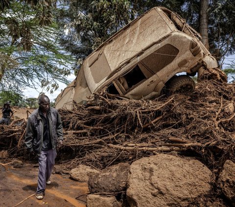 Warga berjalan di dekat sebuah mobil yang tersapu banjir bandang di Desa Kamuchiri, Kota Mai Mahiu, Kenya, Senin (29/4/2024). Terjangan banjir bandang dan tanah longsor di Mai Mahiu, yang menyapu rumah-rumah dan mobil, menewaskan sedikitnya 45 orang dan melukai lebih dari 110 lainnya. Luis Tato/AFP<br>