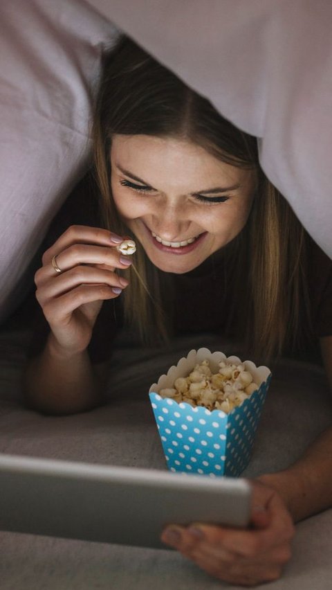 Seorang Wanita Sedang Menonton Film di Tablet Sambil Memakan Popcorn (freepik)