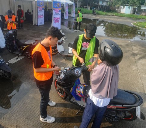 Peserta mengantarkan sepeda motornya yang akan diberangkatkan ke kampung halaman dalam program mudik gratis Kemenhub di Terminal Pondok Cabe, Tangerang Selatan, Banten, Jumat (5/4/2024). Mudik gratis untuk pengendara sepeda motor ini  diselenggarakan Direktorat Jenderal Perhubungan Darat Kementerian Perhubungan (Ditjen Hubdat Kemenhub). Merdeka.com/Arie Basuki