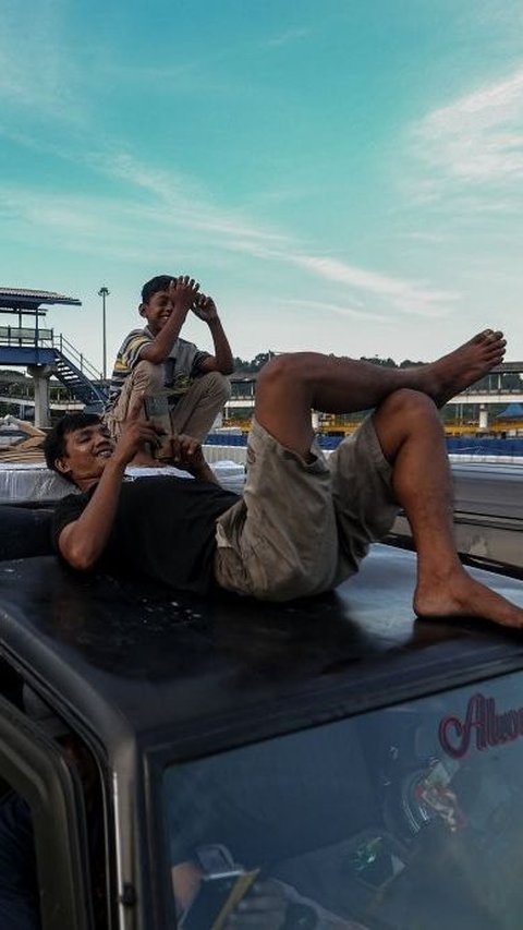 Seorang pemudik bermain dengan gadgetnya saat menikmati antrean panjang di Pelabuhan Merak ketika bersantai di atap mobilnya. Foto: liputan6.com / Angga Yuniar