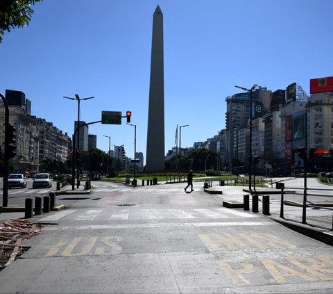 Seorang warga menyeberangi jalanan sepi di dekat Monumen Obeliks, Buenos Aires, Argentina, pada Kamis (9/5/2024). Buenos Aires menjelma bak kota mati ketika serikat buruh Argentina menyerukan aksi mogok massal kepada para pekerja di berbagai sektor. Foto: Luis Robayo/AFP