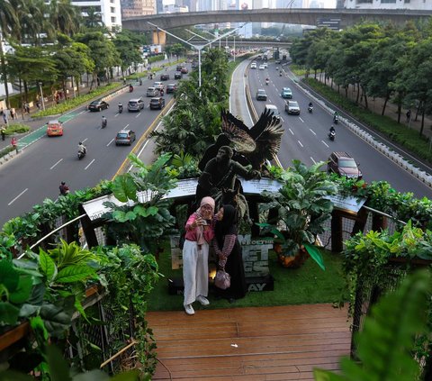 Warga berswafoto di Jembatan Penyeberangan Orang (JPO) Phinisi di Jalan Jenderal Sudirman, Jakarta, Jumat (10/5/2024). JPO Phinisi tiba-tiba menjelma bak hutan belantara. Jembatan estetik itu dipenuhi dedaunan dan akar-akar tumbuhan yang menjuntai. Liputan6.com/Herman Zakharia