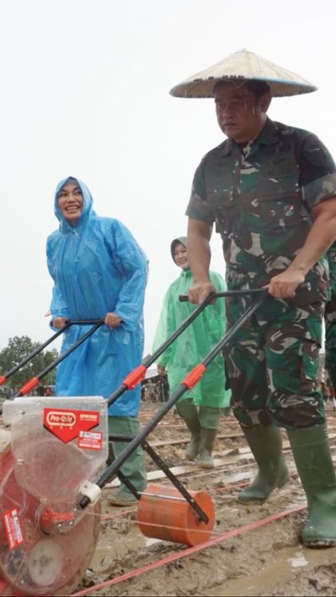 Momen Istri Kasad Hujan-hujanan Pakai Jas Hujan Dampingi Suami, Sang Jenderal Pakai Topi Caping Turun ke Sawah<br>