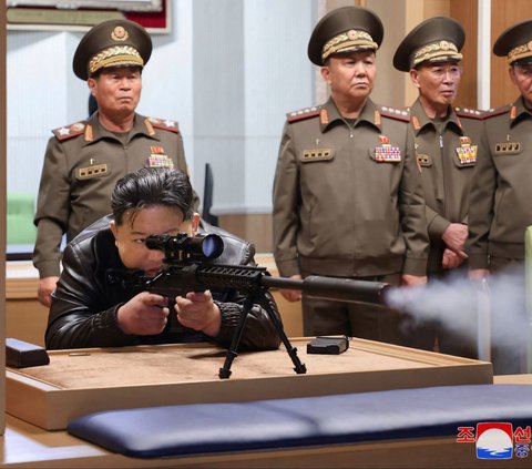 Pemimpin Korea Utara, Kim Jong-un melepaskan tembakan saat menguji coba senapan sniper yang digunakan para penembak jitu. Momen itu terekam ketika Kim mengunjungi sebuah perusahaan industri pertahanan nasional di lokasi yang dirahasiakan, pada Senin (13/5/2024). KCNA VIA KNS/AFP