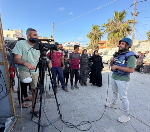 Jurnalis Palestina Sami Shehada (kiri), yang satu kakinya diamputasi, melakukan peliputan di tengah konflik Israel dan kelompok Hamas di Deir Al -Balah, Jalur Gaza, pada 13 Mei 2024. Sambil memegang kamera di satu tangan dan kruk di tangan lainnya, Sami Shehada kembali bekerja setekah salah satu kakinya diamputasi karena terluka saat meliput perang di Jalur Gaza. Foto: REUTERS/Doaa Rouqa<br>