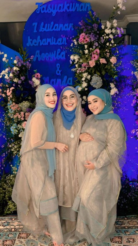 The three of them wear cream-colored clothing combined with a blue hijab.