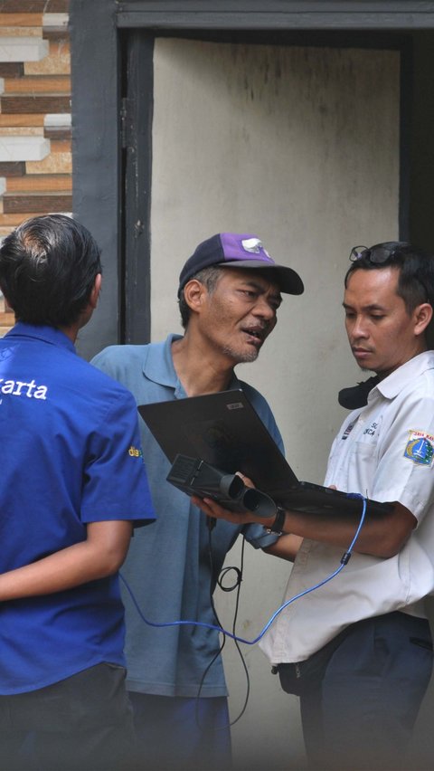 Petugas Dukcapil DKI melakukan perekaman e-KTP terhadap Suradi, warga penyandang disabilitas gangguan jiwa (ODGJ), di Jalan Waru RT004/02, Cilangkap, Jakarta Timur, Rabu (15/5/2024). Foto: Merdeka.com/Imam Buhori