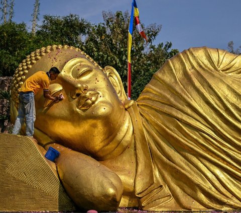 Pengurus memandikan patung Buddha Maha Paranibbana, yang biasa disebut Buddha Tidur, di Maha Vihara Mojopahit, Mojokerto, Jawa Timur, pada Rabu (16/5/2024). Pembersihan patung Buddha Tidur ini dilakukan menjelang perayaan Hari Raya Waisak, pada 23 Mei 2024. Foto: Juni Kriswanto/AFP
