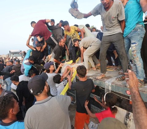 Dalam upaya untuk bertahan hidup, para pengungsi Palestina terpaksa membongkar paksa truk berisi bantuan kemanusiaan yang baru keluar dari Dermaga Trisula yang didirikan oleh Amerika Serikat. Foto: REUTERS / Ramadan Abed<br>