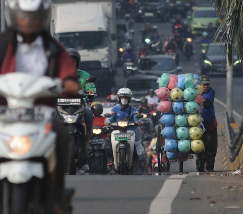 Seorang pedagang keliling mendorong gerobaknya dengan berjalan kaki saat melewati flyover di Buaran, Jakarta, Kamis (2/5/2024). Flyover Buaran sangat berbahaya bagi pejalan kaki. Pasalnya, jalan layang ini tak dilengkapi ruang bagi pejalan kaki, baik itu pembatas maupun trotoar. Foto: Merdeka.com/Imam Buhori