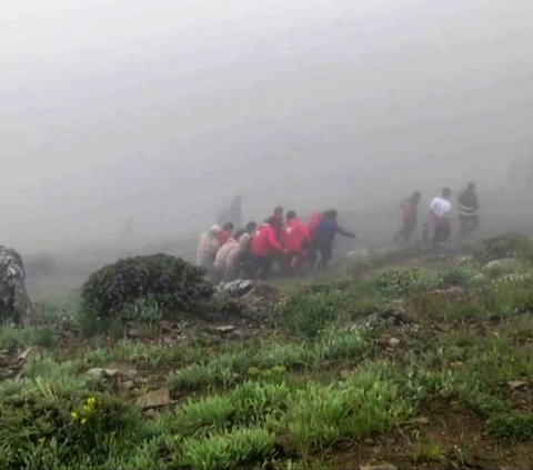 Gambar yang diambil dari rekaman video yang dirilis oleh Bulan Sabit Merah Iran pada tanggal 20 Mei 2024 memperlihatkan proses evakuasi yang dilakukan tim SAR terhadap korban kecelakaan helikopter rombongan presiden Iran di daerah pegunungan,  provinsi barat Azerbaijan Timur di barat laut Iran. Foto: Iranian Red Crescent / AFP<br>