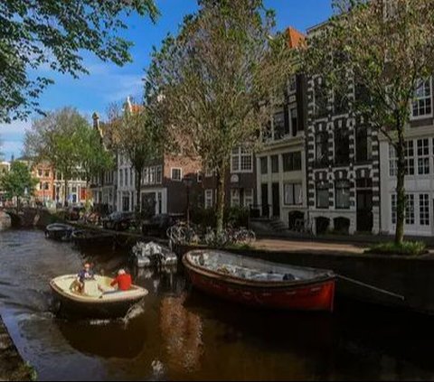 Sebuah kapal berlayar melewati kanal di kota Amsterdam, Belanda, Selasa (22/05/2024). Amsterdam dikenal di seluruh dunia karena kanal-kanalnya yang indah melintasi kota. Merdeka.com/Arie Basuki