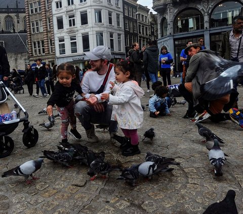 FOTO: Serunya Akhir Pekan Berinteraksi dengan Ribuan Merpati di Dam Square, Amsterdam