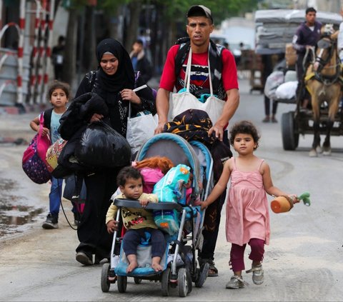 Seorang pria bersama keluarganya membawa barang bawaan saat melarikan diri dari Rafah, Jalur Gaza, Palestina, pada Selasa (28/5/2024). Serangan biadab Israel yang menghantam kamp pengungsian di Rafah membuat warga Jalur Gaza ketakutan. Foto: REUTERS/Hatem Khaled