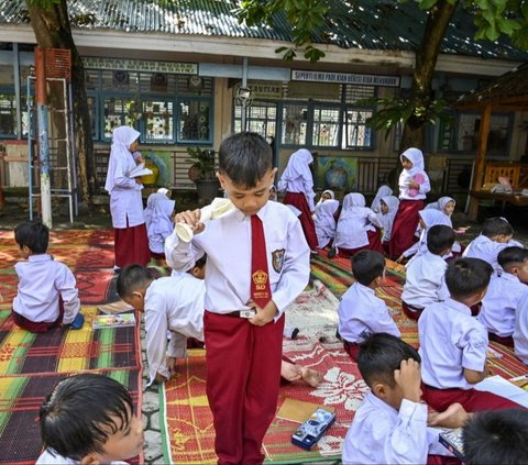 Seorang siswa meminum air selama pembelajaran di luar kelas di Sekolah Dasar Negeri (SDN) 16 Banda Aceh, Aceh, pada 7 Mei 2024. SDN 16 Banda Aceh menggelar pembelajaran di ruang terbuka untuk menghadapi cuaca panas ekstrem. Foto: Chaideer Mahyuddin/AFP